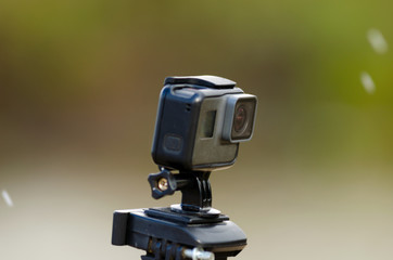 Action camera is recording video on a blurred background of snow and grass with a river.
