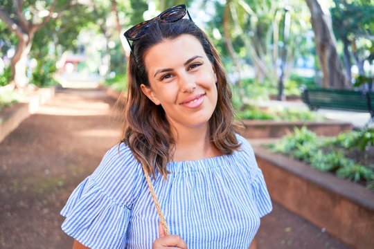 Young beatiful woman smiling happy and cheerful at green park on a sunny day of summer