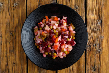 Traditional Russian dish vinaigrette. Vegetarian salad of beets, potatoes, carrots, pickles, green peas and onions. Healthy eating concept.