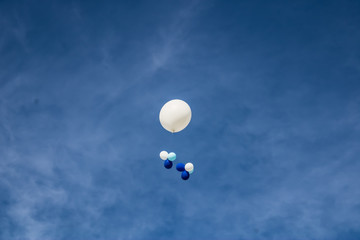 Big white helium balloon with the smaller blue and white ballons with the blue sky background, holiday balloons in the sky, celebraion with ballons - Image
