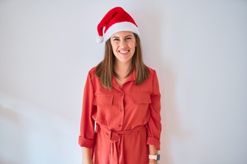 Young beautiful woman smilling happy wearing red dress and a santa claus hat at christmas
