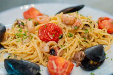 Spaghetti pasta with shrimp, mussels, tomatoes and cheese, close-up, side view. Tasty, traditional food Italians