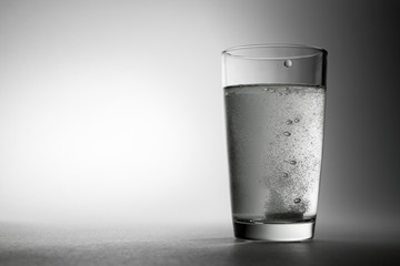 Fizzy pill is in glass of water background.