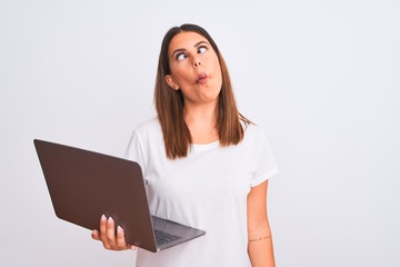 Beautiful young woman working using computer laptop over white background making fish face with lips, crazy and comical gesture. Funny expression.