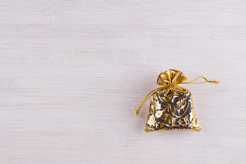 Gift in a golden bag on a light background. Top view. The concept of sales, shopping, Christmas holidays and birthday, Valentine. Copy space