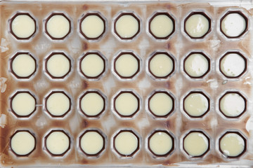 the manufacture of chocolates. white chocolate pour into round shapes.