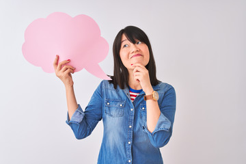 Young beautiful Chinese woman holding cloud speech bubble over isolated white background serious face thinking about question, very confused idea