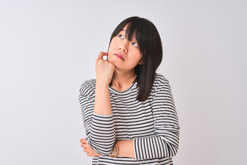 Young beautiful chinese woman wearing black striped t-shirt over isolated white background with hand on chin thinking about question, pensive expression. Smiling with thoughtful face. Doubt concept.