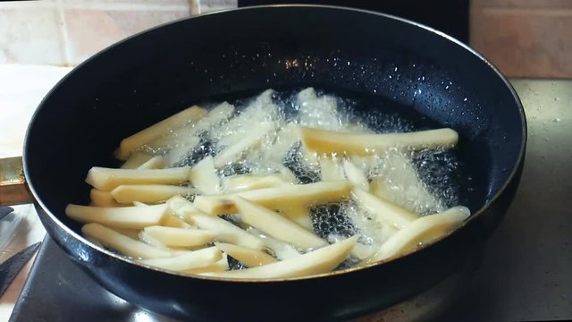 the process of frying chopped potatoes in boiling vegetable oil in a teflon iron pan