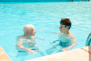 Obraz na płótnie Canvas sports grandfather and grandson communicate in swimming pool