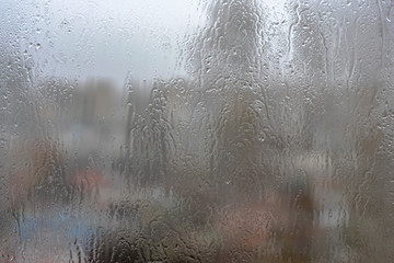 Drops of water on a window pane against a foggy cityscape