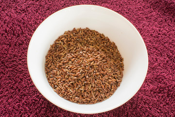 Red rice on a ceramic dish. Semi-polished rice,a certain amount of the reddish bran shell remains on the grains. Because of this, it cooks somewhat faster than unpolished brown rice.