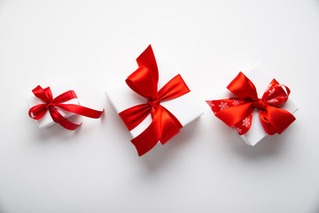 White gifts with red ribbon, present on white background top view. Merry Christmas and Happy Holidays. New Year. Valentine's day. Birthday.