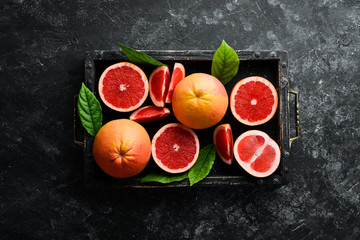 Fresh grapefruits in a wooden box. Citrus fruits on stone background. Top view. Free copy space.