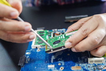 E-waste, technician repairing inside of hard disk by soldering iron. Integrated Circuit. the...