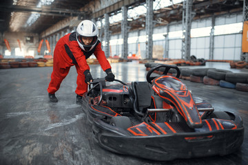 Fototapeta premium Racer in helmet pushing a go kart car, karting