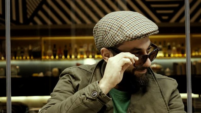 An obvious adult male adult flirter at a cafe checking out women.Stereotype of  European man winking at females passing by,taunting smiling and flirting in an apparent/blatant way.