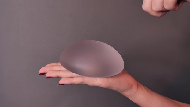 Girl shows, examines, plays with silicone implant for breast augmentation