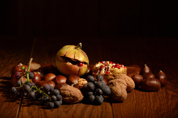 Autumn fruit composition with pommegranate, black grapes, nuts and chestnuts on a wooden table