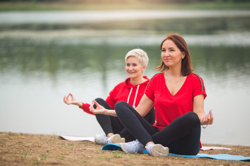 two stylish adult women do outdoor sports in the summer near the lake