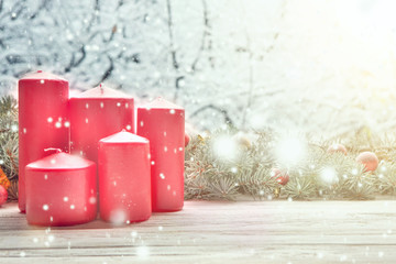 Five red candles with a Christmas tree and Christmas decorations against the background of falling snow and snow-covered forest. Fairy tale