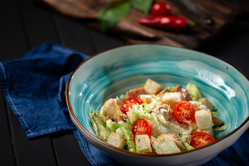 Caesar salad in a bowl with fried chicken, Parmesan cheese, croutons and lettuce, rustic style