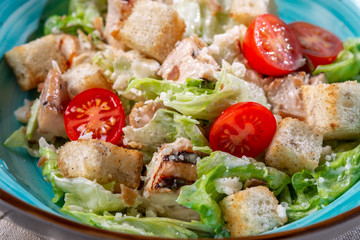 Caesar salad in a bowl with fried chicken, Parmesan cheese, croutons and lettuce, rustic style, close up