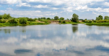 View of the mirror surface of the lake and the shore with trees