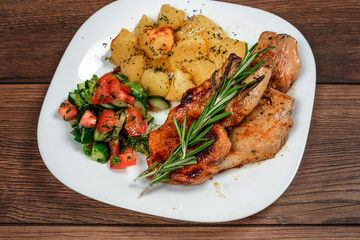 Pork steak, baked potatoes, salad and a sprig of rosemary. Recipe, cooking meat.