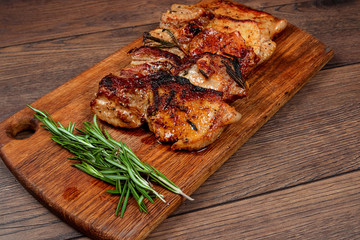 Pork steak and sprig of rosemary on a wooden cutting board. Recipe, cooking meat.