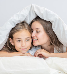 Mom and her daughter secretly talk under the covers