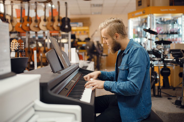 Fototapeta na wymiar Musician trying to play on piano in music store