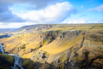 Tourist takes photo on mobile phone of second highest waterfall in Iceland - Haifoss. Picturesque sunrise view of deep canyon. Travel to Iceland. Beauty of nature concept background..