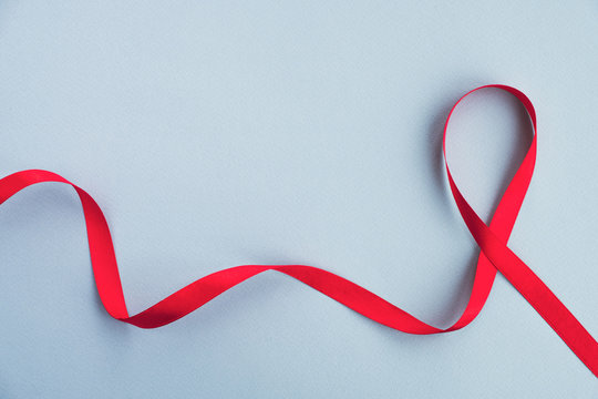 Red ribbon awareness Aids on a light blue background. Medicine concept, World Aids day campaign. Top view, copy space