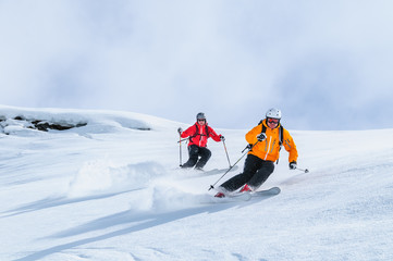 Zwei Skifahrer befahren gemeinsam einen steilen Hang