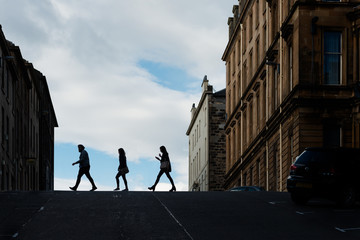 People in silhouette crossing a street in central Glasgow.