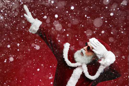 Waist up portrait of cool Santa dancing over red background with snow falling, copy space