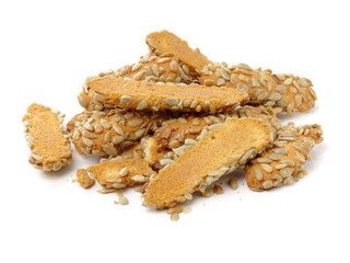 A broken breadstick with sunflower seeds and crumbs on white background