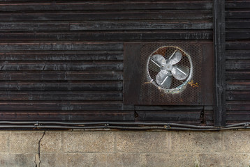 extractor fan on outside of wooden outbuilding 