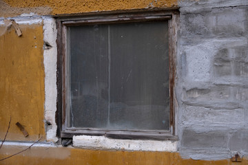 Aged weathered street wall with a window.