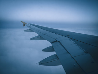 Fototapeta premium Image of airplane wing flying in bad weather conditions, fog and clouds
