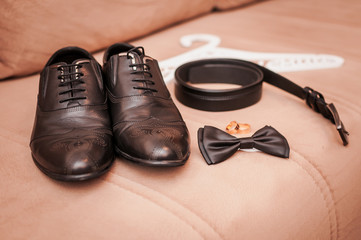 Black bow tie belt and shoes pair of wedding rings on the sofa