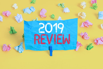 Conceptual hand writing showing 2019 Review. Concept meaning New trends and prospects in tourism or services for 2019 Colored crumpled paper empty reminder white floor clothespin