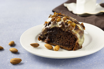 Delicious chocolate cake with raisins and cream. Piece of Chocolate Cake on a Plate. Sweet food. Sweet dessert. Light bakcground. Close up.