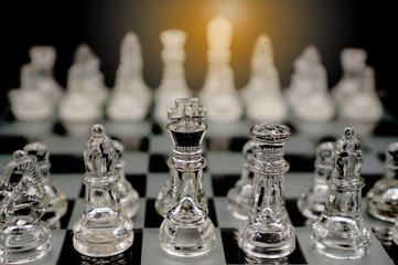Glass chess pieces on chessboard ,represent business competition strategy and leadership concept