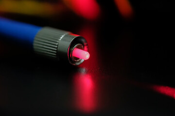 Closeup of connectors of optical fiber network cable. The laser shines from the optical cable.