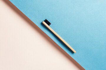 Eco-friendly sustainable bamboo charcoal tooth brush on blue and peach background, selective focus