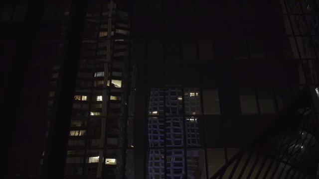 Skyscraper reflection with glass windows at business district in Paris at night, slow steadicam movement side track, Medium shot with reflections. Futuristic modern building with lights. 4K UHD.