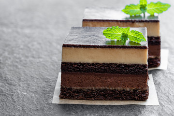 Chocolate and coffee cake slices on black stone background
