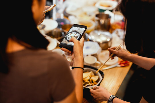 Female Friends having dinner party taking picture of food post on social media.